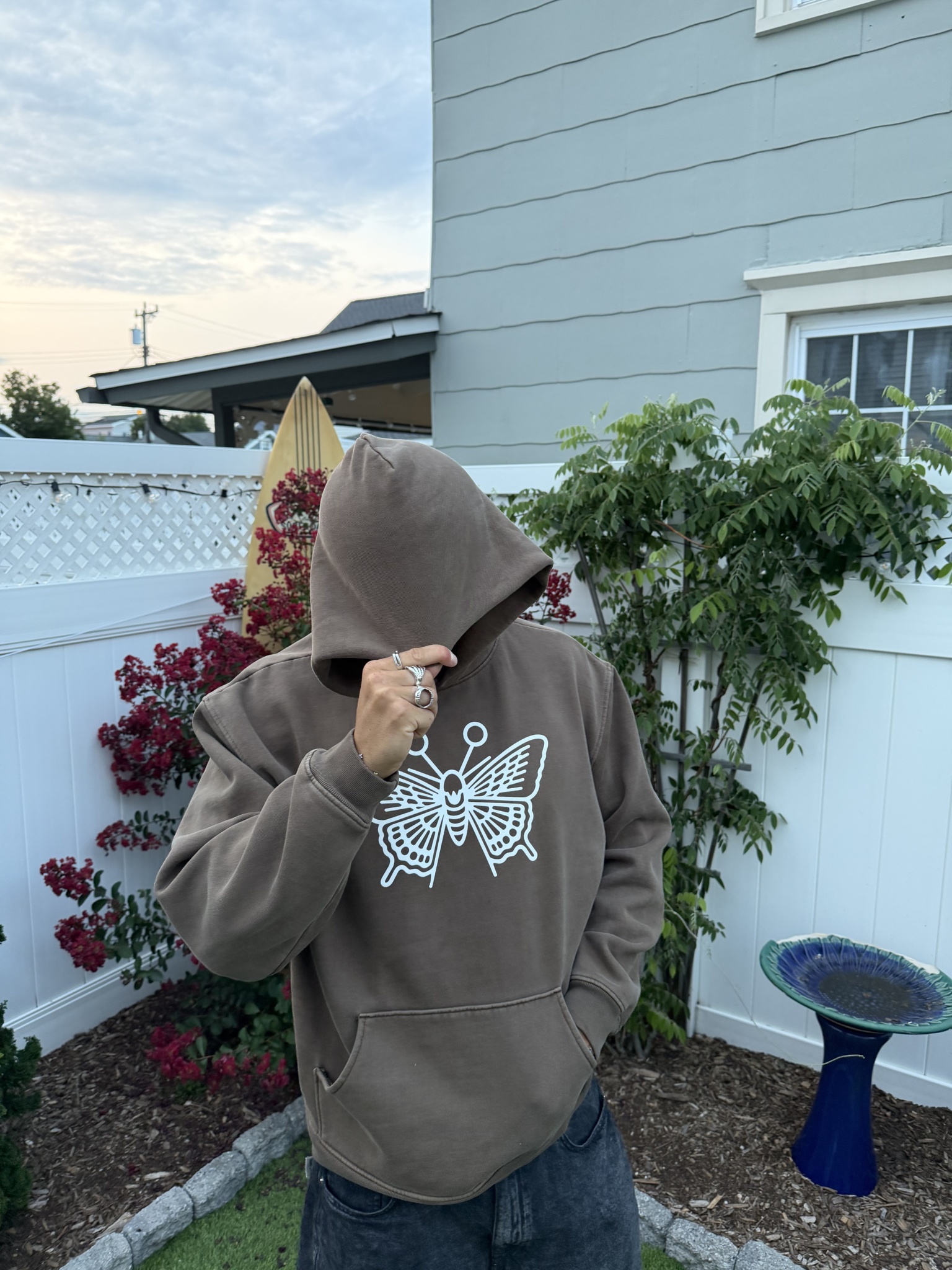 Person wearing a brown hoodie with a white butterfly design